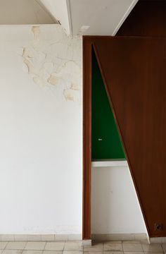 an open door in a room with white walls and tile flooring on the ground