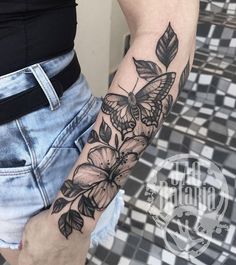 a woman's arm with a butterfly and flowers tattoo on the left side of her body