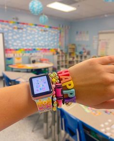 a child's hand holding onto an apple watch with colorful bracelets on it