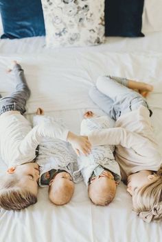 two young boys laying on top of a bed next to each other