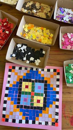 several boxes filled with different colored pieces of paper on top of a wooden table next to each other