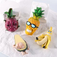 three small figurines in the shape of bananas and pineapples