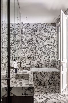 a bathroom with marble walls and flooring next to a bathtub in the corner