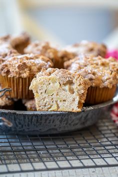 some muffins are sitting in a pan on a cooling rack and one is half eaten