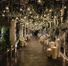 an outdoor event with candles and greenery on the walls, surrounded by white pillar lights