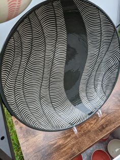 a black and white plate sitting on top of a wooden table next to red cups