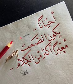 a red pencil sitting on top of a piece of paper that has writing in arabic