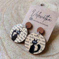 the earrings are decorated with black and white cats on wood discs, which have been cut out to look like cat faces