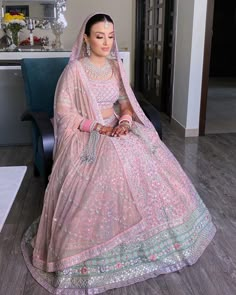 a woman sitting in a chair wearing a pink lehenga