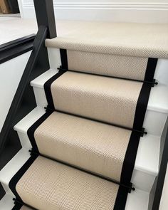 a set of stairs with white carpet and black trim on the bottom handrails