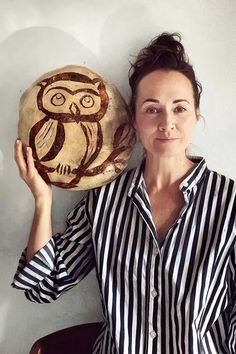 a woman holding up a carved owl on top of a wooden object in front of her face