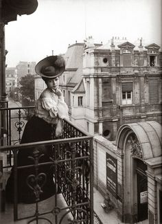 a woman standing on top of a balcony next to a building