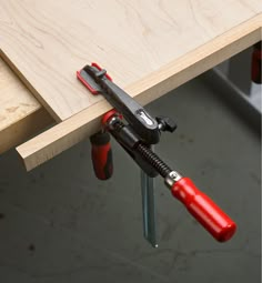 a pair of screwdrivers are attached to a piece of workbench that is being used as a clamp