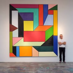 a man standing in front of a colorful painting