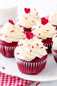 cupcakes with white frosting and red sprinkles on a plate