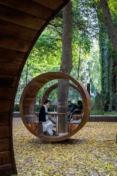 two people sitting on benches in the middle of a park with trees and leaves all around them