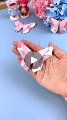 someone is holding some origami pieces in their hand and they are on the table