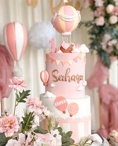 there is a pink and white cake with balloons in the sky on top of it