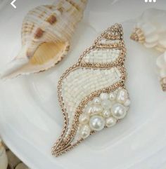 shells and pearls on a white plate next to seashells