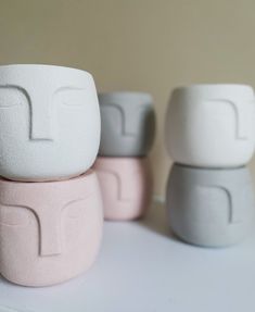 three small white and pink vases sitting on top of a table next to each other