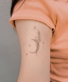 a woman with a small flower tattoo on her left side ribcage and the moon behind it