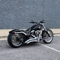 a black motorcycle parked in a parking lot next to a gray wall and white lines