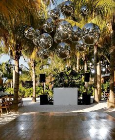 an outdoor event with disco balls hanging from the ceiling and palm trees in the background