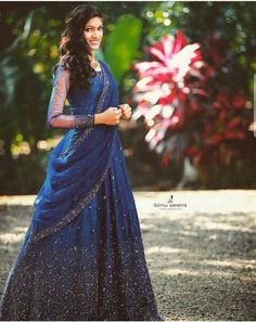 a woman in a blue dress is posing for the camera with her hand on her hip