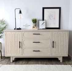 a white sideboard with two plants on top and pictures above it in a living room