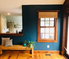 a wooden bench sitting in front of a window on top of a hard wood floor