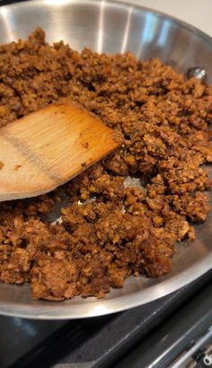 a wooden spoon in a metal bowl filled with food