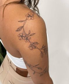 a woman with a flower tattoo on her arm and shoulder is looking at the camera