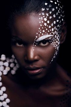 a woman with white paint on her face and body is shown in the dark background