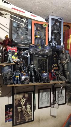 batman action figures are displayed on shelves in a room filled with pictures and memorabilia,