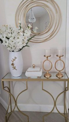 a white vase filled with flowers sitting on top of a table next to a mirror