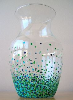 a glass vase with blue, green and white speckles on the bottom sitting on a table