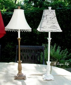 two lamps sitting on top of a table next to each other in front of trees