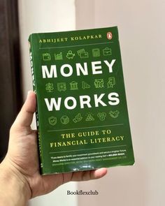 a person holding up a green book with money works on it's front cover