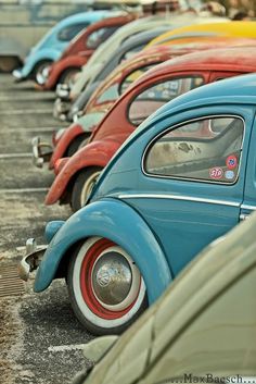 an old vw bug parked in a parking lot next to other classic volkswagen cars