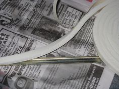 scissors are laying on top of newspapers with paper in the foreground and rolled up newspaper behind them