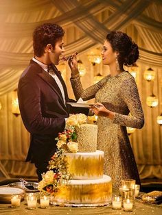 a man and woman standing next to each other in front of a cake