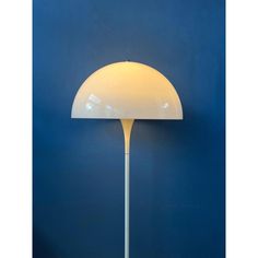 a white floor lamp against a blue wall