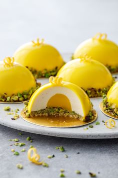 some yellow desserts are sitting on a white plate with green sprinkles