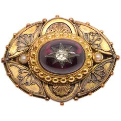 14-carat gold clasp with garnet and diamond. 14-carat gold-plated oval brooch finished with a gold-plated beaded cord adorned at the front with a curved composition that leaves smooth spaces for simplified plant motifs and two semicircles on the vertical axis of the smaller side which cover other plant elements. In the center, framed by a band with strings and pearls in gold and with two small pearls on the major axis (in the triangular spaces that leave the curves already mentioned), is placed Ceremonial Gold Brooches With 17 Jewels, Luxury Oval Cabochon Brooches, Luxury Oval Jewelry For Opera, Victorian Oval Jewelry For Opera, Elegant Yellow Gold Medallion Brooches, Formal Jeweled Yellow Gold Jewelry, Formal Yellow Gold Jeweled Jewelry, Oval Jeweled Gold Jewelry, Elegant Cabochon Jewelry For Ceremonial Occasions