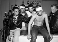 black and white photograph of four men sitting on a bench with one man wearing a bandaged headband