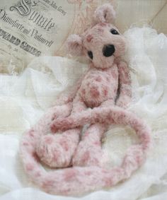 a pink teddy bear sitting on top of a white cloth covered bed with an old fashioned sign in the background