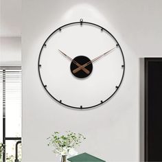 a large clock mounted to the side of a wall next to a vase with flowers