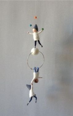 two small figurines are hanging from a string in the shape of a circle