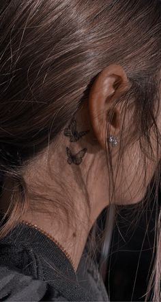 a close up of a person's ear with a butterfly tattoo on their left side