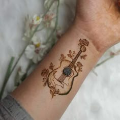 a woman's arm with a tattoo on it that has a guitar in the middle